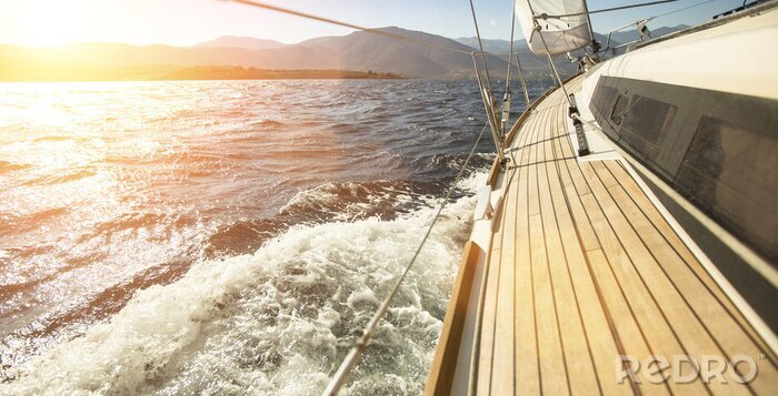 Poster Zeilboot bij zonsondergang bergachtergrond