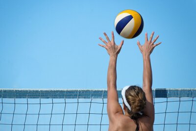 Sticker Beachvolleybal speler springt op het net en probeert de bal te blokken