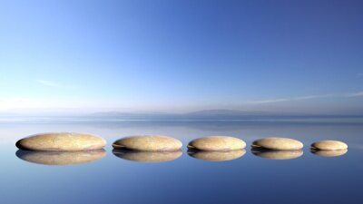 De stenen van Zen rij van groot naar klein in water met blauwe hemel en rustige landschap achtergrond.