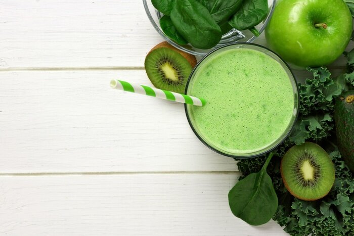 Sticker Groene smoothie vooral oog met boerenkool, avocado, spinazie, appel en kiwi tegen een witte houten achtergrond