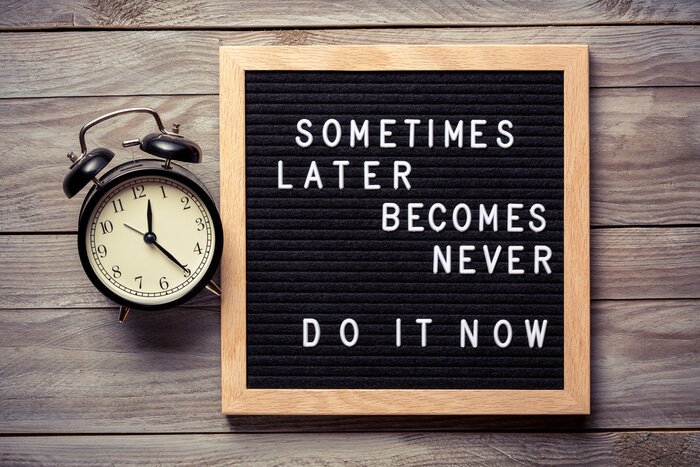 Sticker Inspirational motivational quote Sometimes later becomes never. Do it now words on a letter board on wooden background near vintage alarm clock. Success and motivation concept.