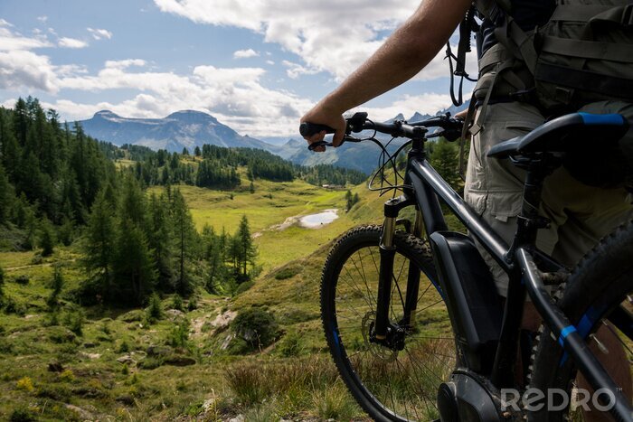 Sticker Jonge volwassen actieve man op berg dragen fietshelm en rugzak kijken naar schilderachtig panorama houden elektrische fiets in zonnige zomerdag buiten.