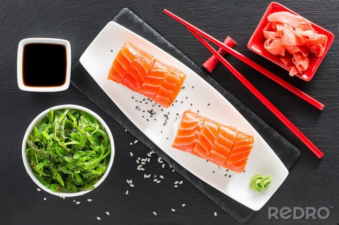 Sticker sushi en groene zeewiersalade op een lei tafel