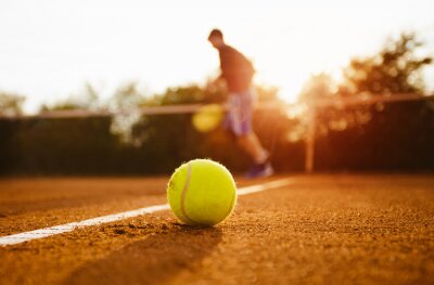 Tennisbal en silhouet van de speler op een gravelbaan