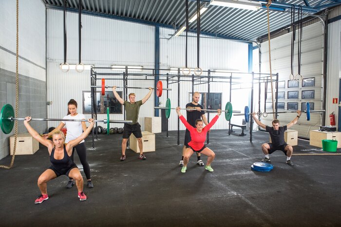 Sticker Trainers Assisting Athletes In Exercising With Barbells